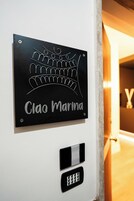 Une enseigne au design stylisé, avec l’inscription « Ciao Marina », est fixée à un mur.