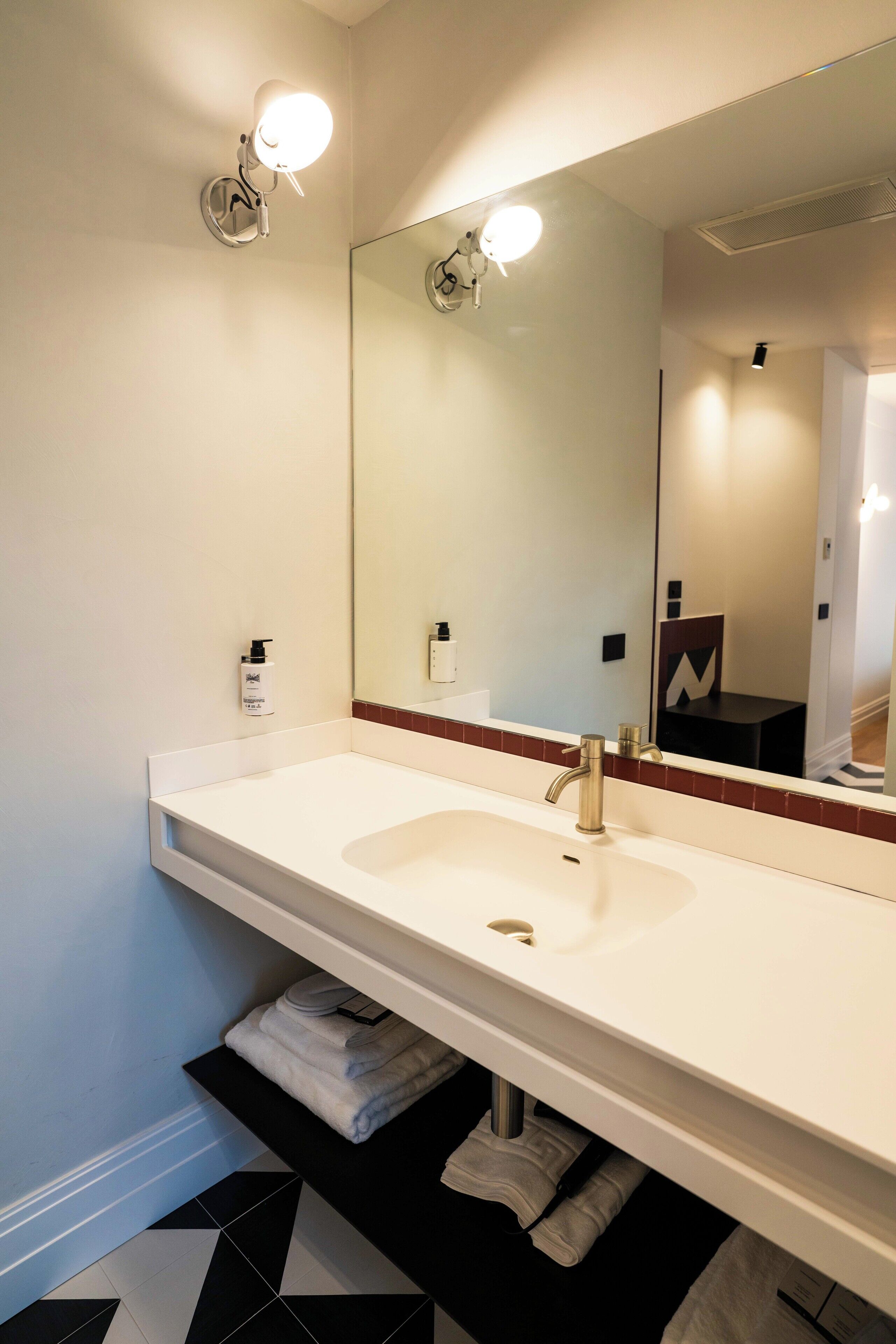 A bathroom with a white sink, a large mirror, and a towel rack.