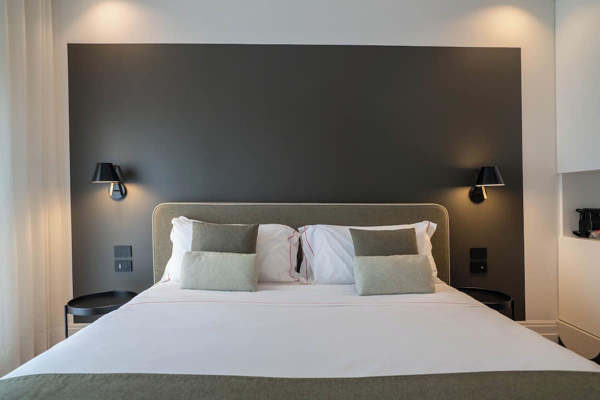 A neatly made bed with pillows, two wall-mounted lamps, and a bedside table.