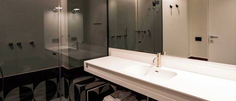 A modern bathroom with a glass-enclosed shower, a large mirror, and a white sink.