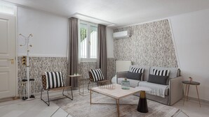 A modern living room with a sofa, coffee table, and patterned wallpaper. - Athenian Secret Glyfada (Glyfada)