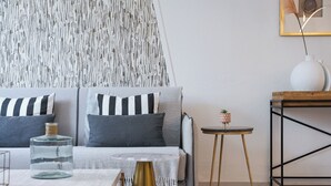 A modern living room with a grey sofa, striped pillows, a glass vase, and a small table with a plant. - Athenian Secret Glyfada (Glyfada)