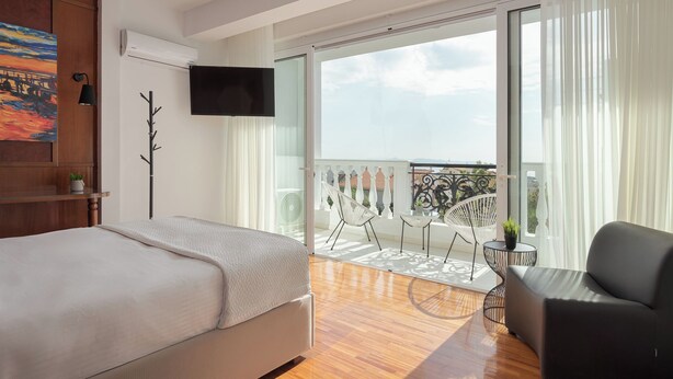 A bedroom with a bed, a TV, a balcony with a view, and a chair. - Athenian Secret Glyfada (Glyfada)