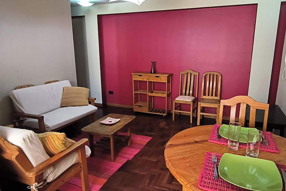 A living room with a sofa, a coffee table, and a dining table set for two.