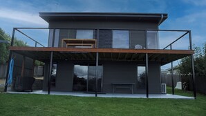 A modern two-story house with a covered patio and large windows.