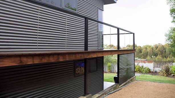 A modern two-story building with a balcony and a garage door.