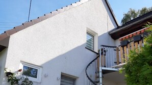 A white building with a spiral staircase, a small window, and a bench.