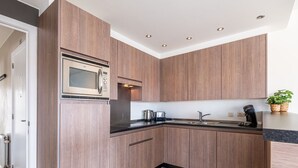 A modern kitchen with wooden cabinets, a built-in microwave, a kettle, and a coffee machine. - Orangerie 202 Close to the Beach and Center (Koksijde)