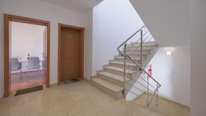 Eine Treppe mit Metallgeländern, einer Holztür und einem Essbereich mit Stühlen und einem Tisch.