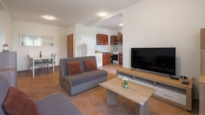 Ein modernes Wohnzimmer mit einem grauen Sofa, einem Holztisch und einem Flachbildfernseher.