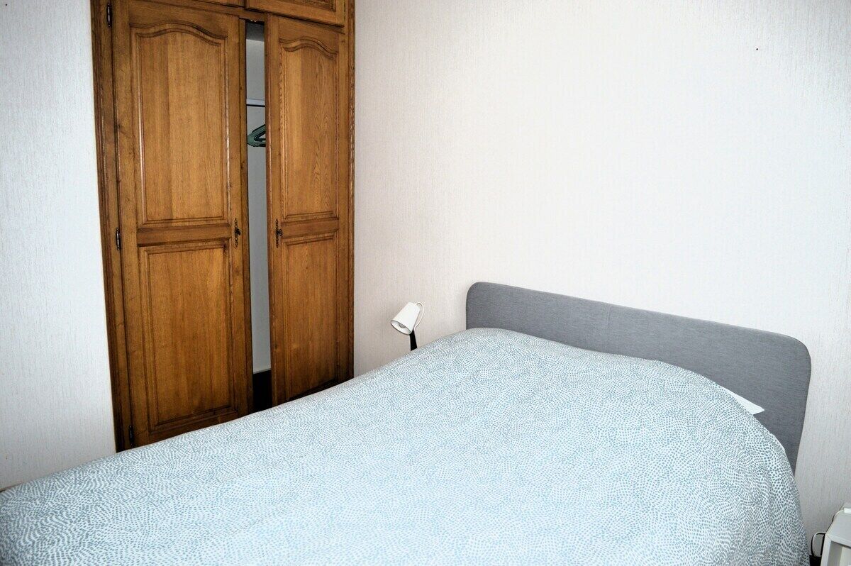 Une chambre à coucher avec un lit, une tête de lit grise et une armoire en bois.