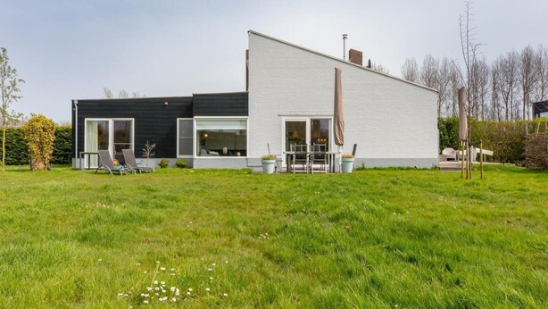 A modern two-story house with a flat roof, large windows, and a spacious lawn. - Holiday Home in Nieuwvliet Near the Beach (Nieuwvliet)
