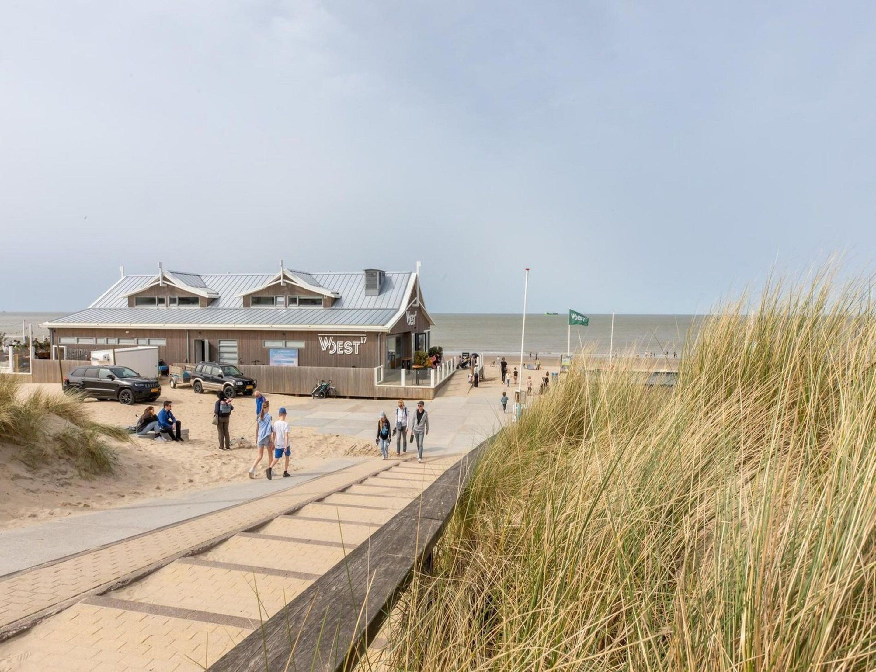 Ein Gebäude direkt am Strand mit einem Schild 'WEST17' und einem gepflasterten Weg, der zum Strand führt.