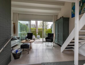 Uma sala de estar moderna com sofá, cadeiras, uma mesa de centro e vista através de grandes janelas.