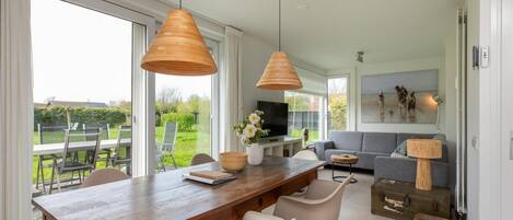 A modern dining area with a wooden table, white chairs, and pendant lights.