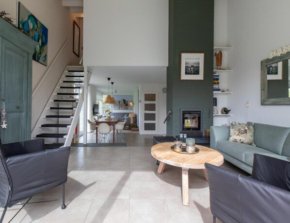 A spacious living area with a staircase, a dining table, and a sofa.