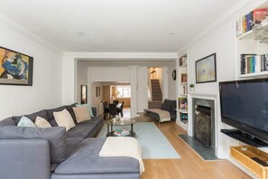 A modern living room with a sofa, coffee table, fireplace, TV, and bookshelves.