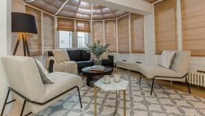 A modern living room with a sofa, armchair, coffee table, and a lamp. - Elegant 3BR Knightsbridge Residence near Harrods (London)