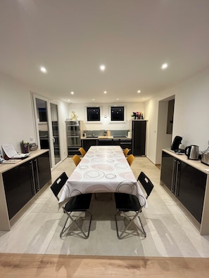 A modern kitchen with a dining area, featuring a large table, chairs, and built-in appliances.