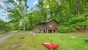 A rustic cabin with a porch, surrounded by lush greenery and a gravel path. - Creek Front Cabin in Pearisburg (Pearisburg)