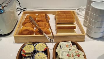 A breakfast tray with bread rolls, butter, and jam packets.