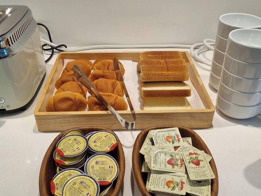 A breakfast tray with bread rolls, butter, and jam packets.