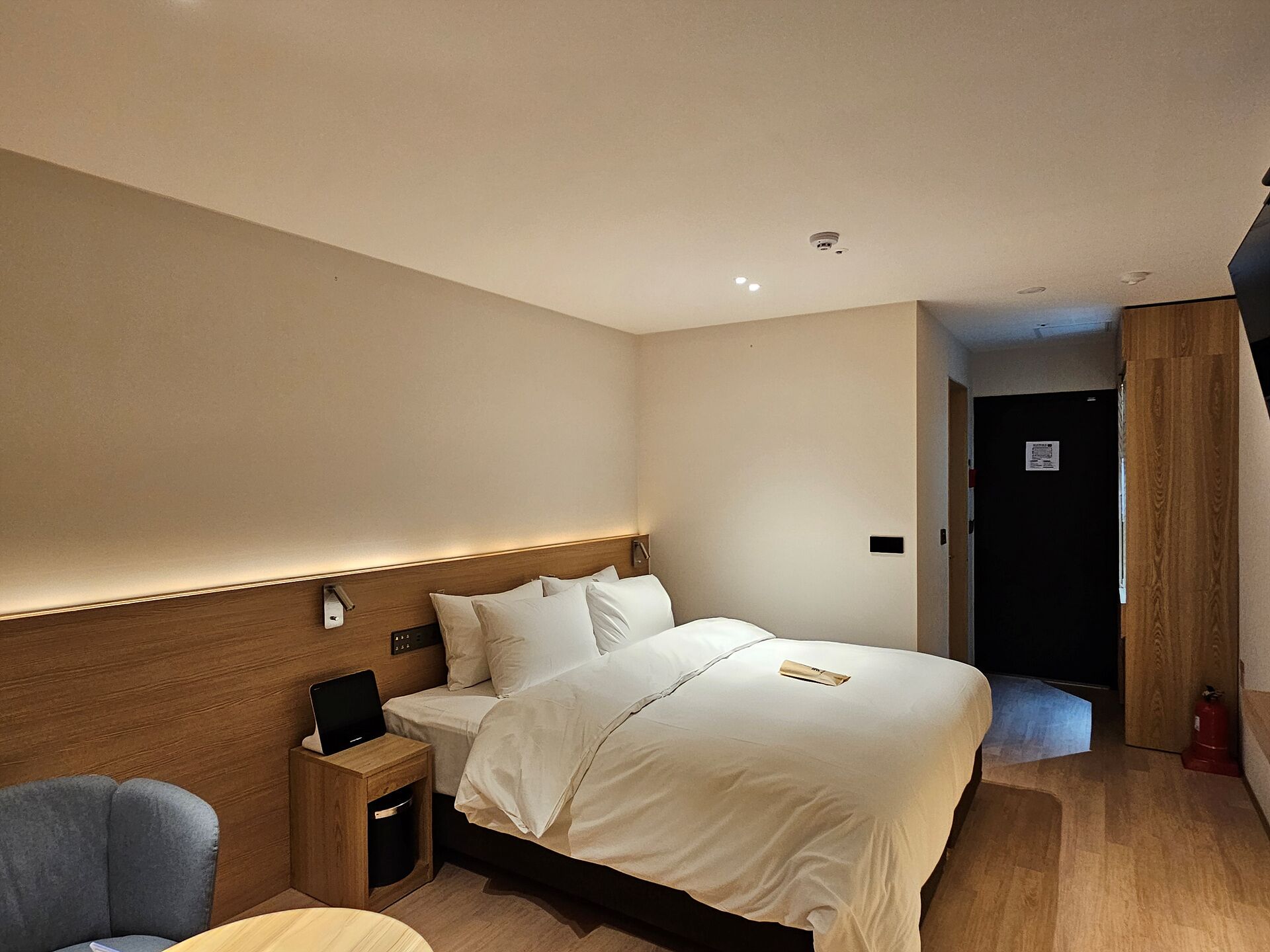 A hotel room with a bed, bedside table, and a chair.