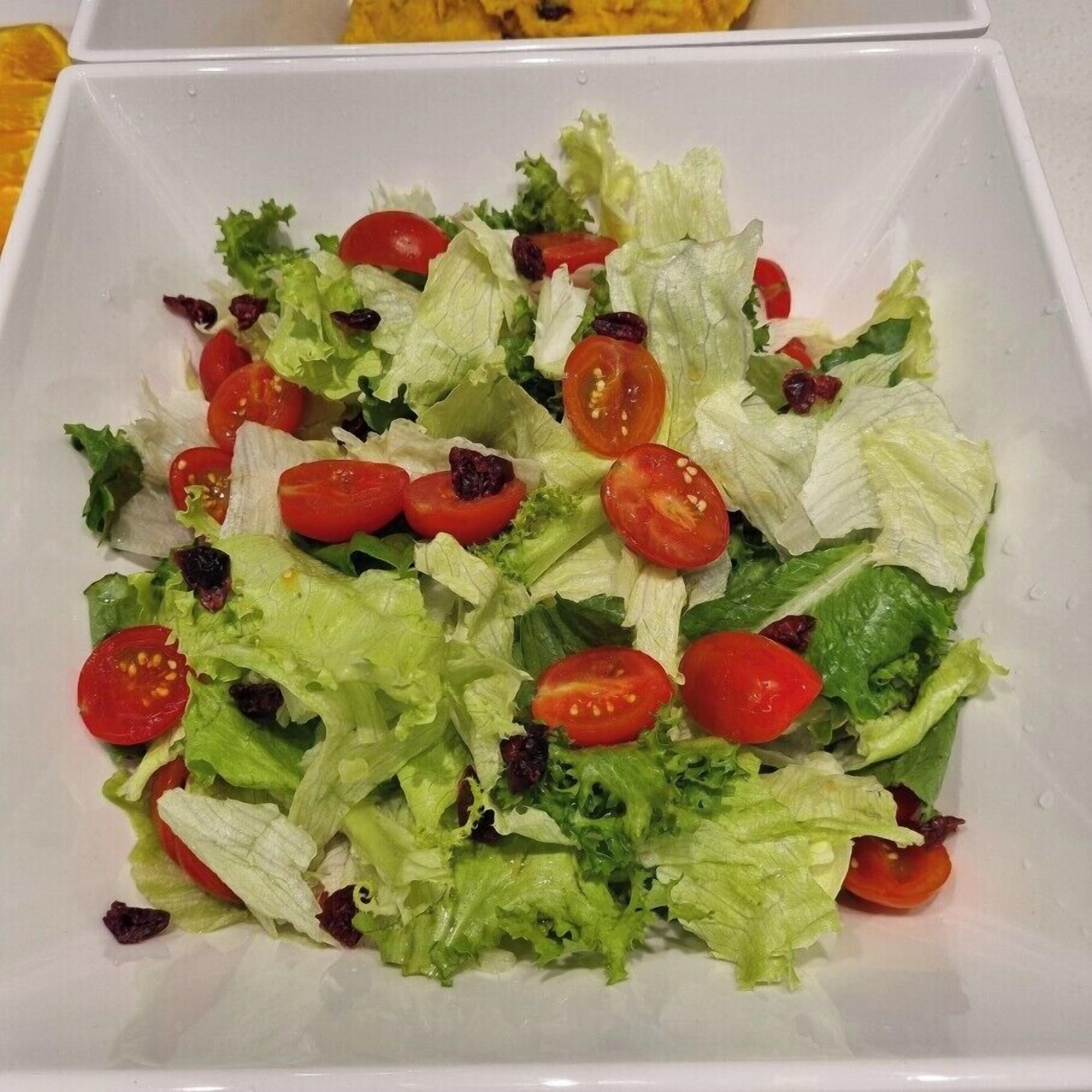 A salad with lettuce and cherry tomatoes on a white plate.
