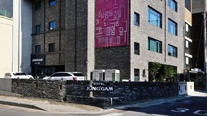 Un moderno edificio de hotel con un cartel llamativo que dice 'Grand Open', varios pisos y fachada de piedra.