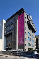 Un moderno edificio de hotel con un cartel llamativo que dice 'Grand Open', varios pisos y fachada de piedra.