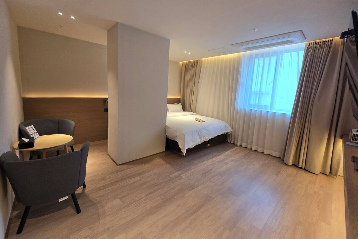 A modern hotel room with a bed, a desk, and a chair.