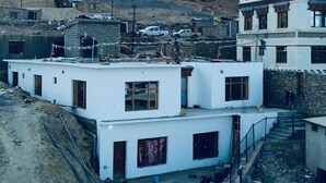 A multi-story building with a flat roof and a staircase leading to the upper floor.