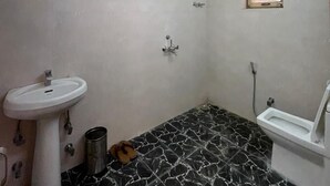 A bathroom with a sink, toilet, shower, and a small window.