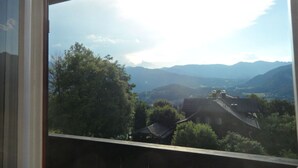 Ein Blick durch ein Fenster auf ein Haus mit Bergblick.