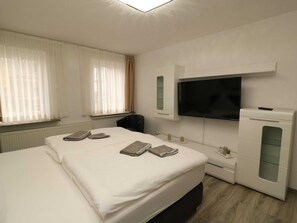 A hotel room with a large bed, a TV mounted on the wall, a small desk, and a cabinet. - Apartment in Essen With Balcony & Garden (Essen)