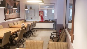 A conference room with a long table and chairs, large windows with blinds, pendant lights, and a fire extinguisher. - Apartment in Essen With Balcony & Garden (Essen)