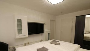 A hotel room with a bed, a TV mounted on the wall, a wardrobe, and a mirror. - Apartment in Essen With Balcony & Garden (Essen)