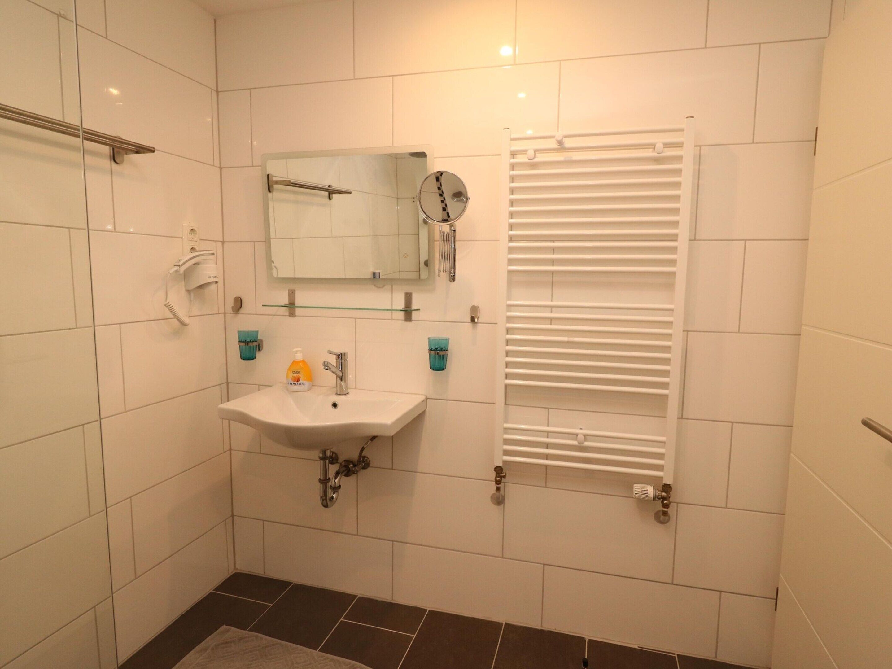 A bathroom with a white sink, mirror, and towel rack.