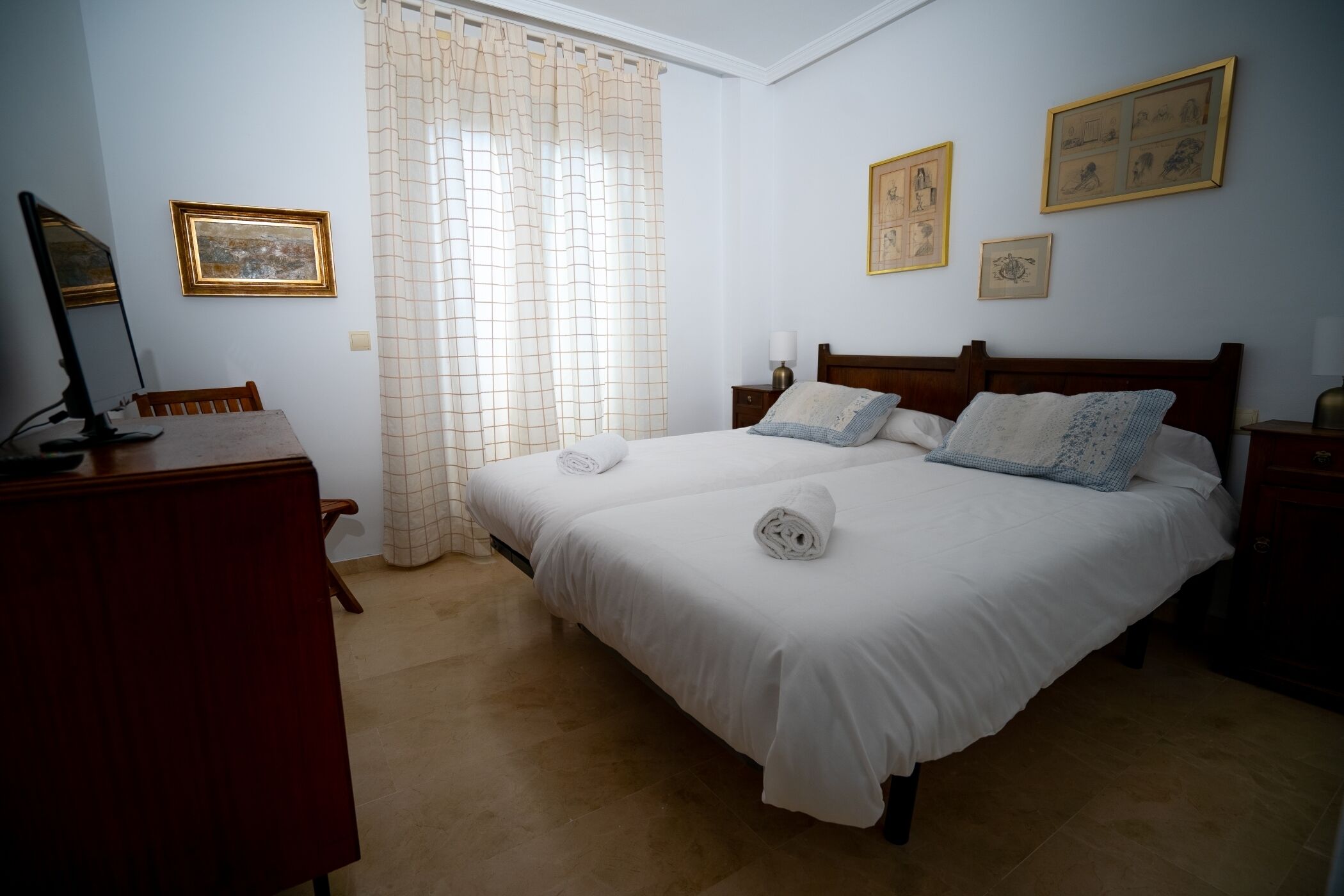 Un dormitorio con cama doble, un escritorio y una silla. Hay dos mesitas de noche con lámparas.