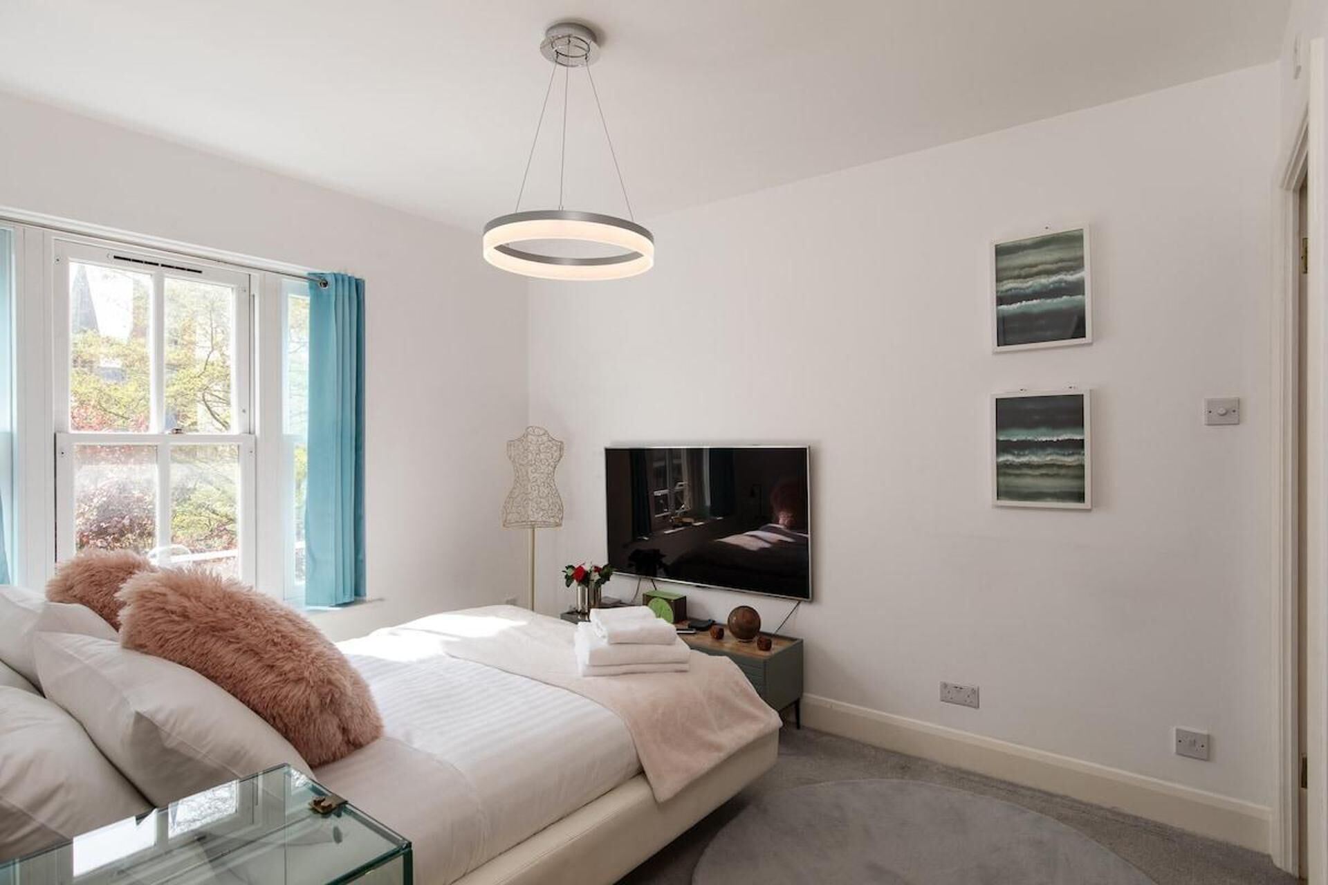 A bedroom with a bed, a TV, and artwork on the wall.