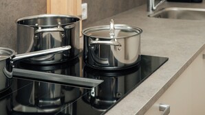 A kitchen with a stove, pots, and a knife block. - Urban Suites (Eindhoven)