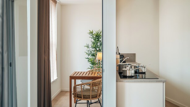 A modern kitchen with a dining area, including a table, chairs, and a potted plant. - Urban Suites (Eindhoven)