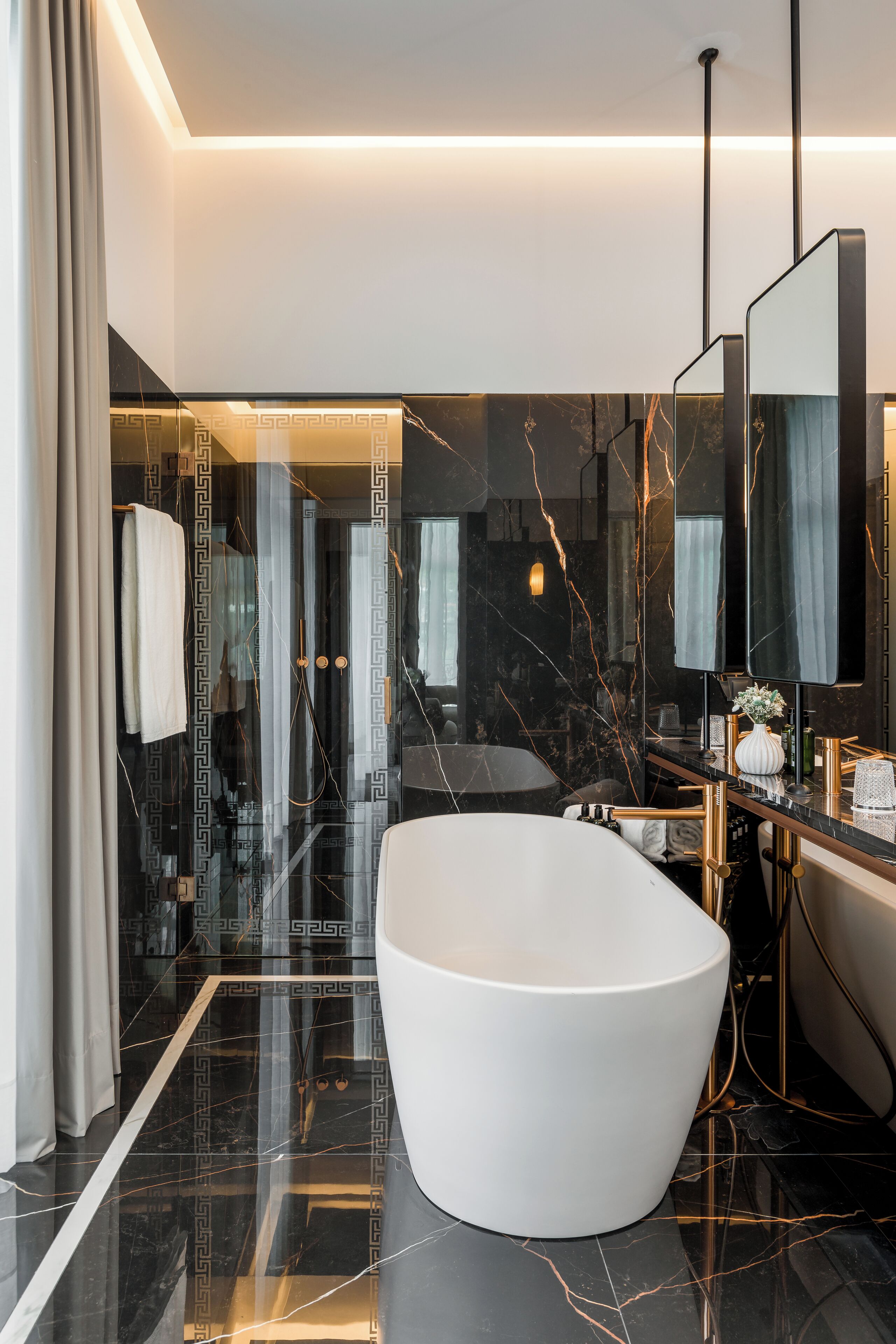 A modern bathroom with a freestanding bathtub, marble flooring, and a large mirror.