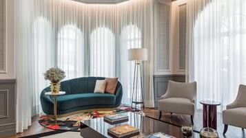 A modern living room with a teal sofa, a round coffee table, and two armchairs.