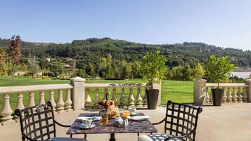 An outdoor dining area with a table set for two, overlooking a scenic hillside.