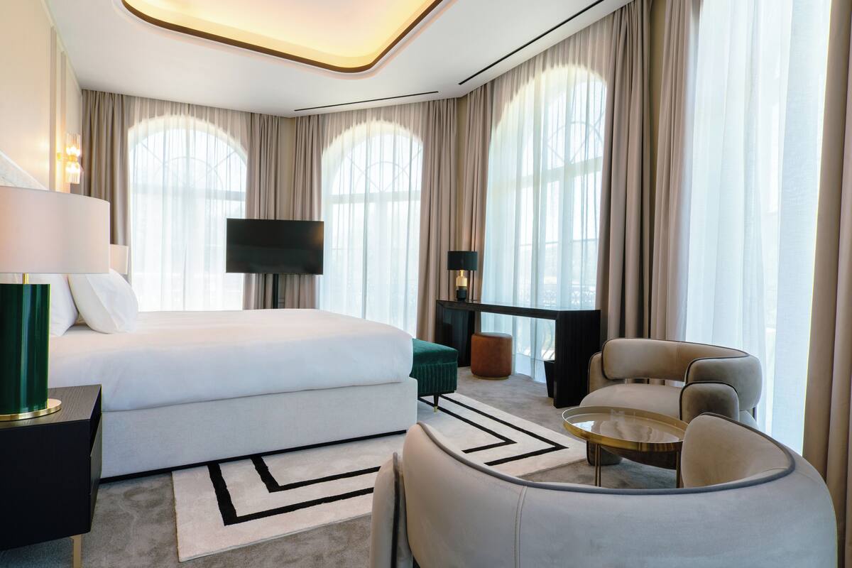 Een moderne hotelkamer met een bed, een televisie, een bureau, een stoel en een bank.