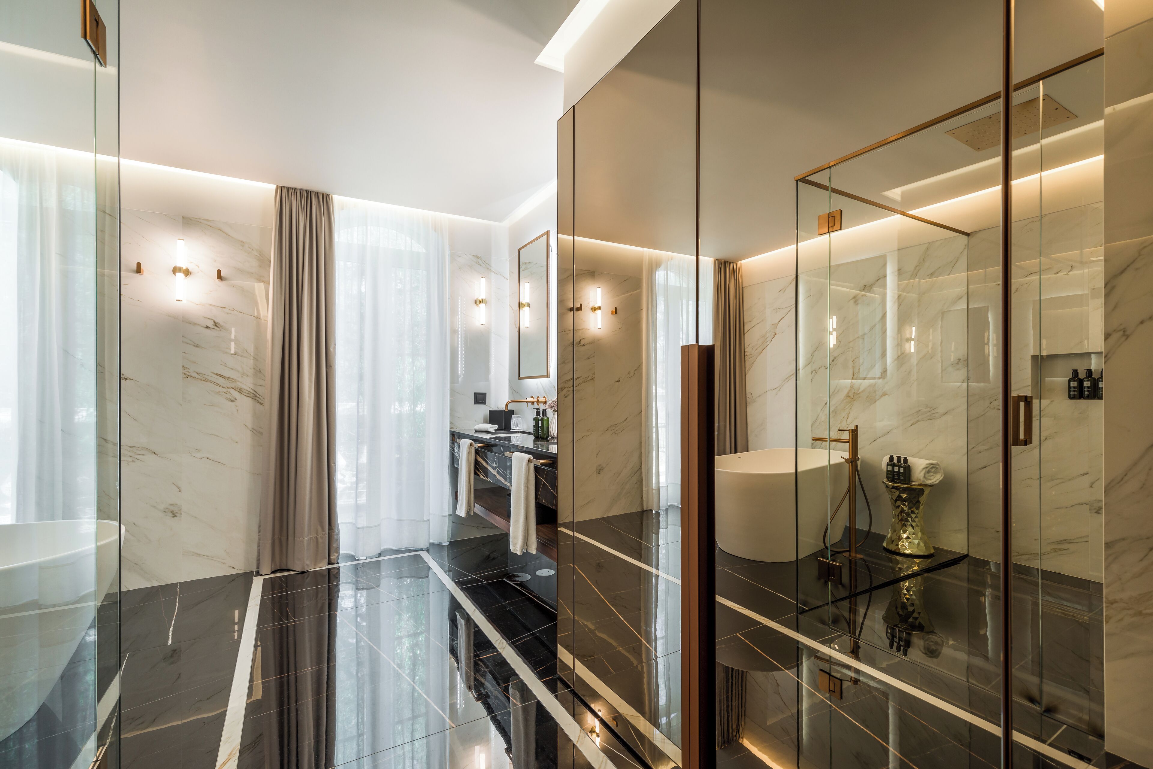 A modern bathroom with a glass-enclosed shower, marble walls, and a vanity with a large mirror.