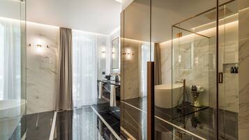 A modern bathroom with a glass-enclosed shower, marble walls, and a vanity with a large mirror.
