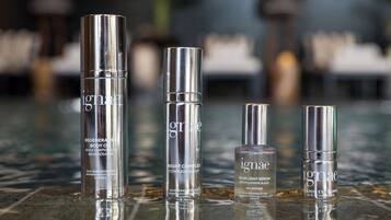 Quatro produtos de cuidados com a pele sobre uma superfície espelhada.