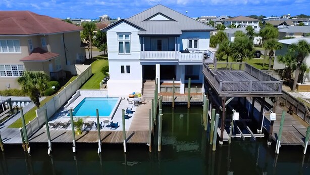 A two-story house with a pool and a dock extending into a body of water. - Waterfront Home w/ Pool, Boat Slip & Private Beach Access – Holiday Isle (Destin)